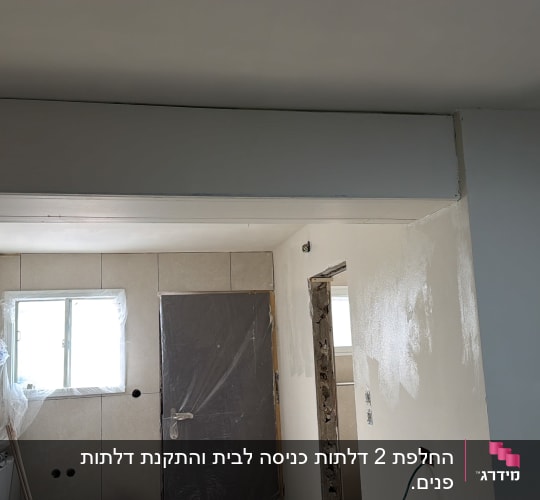 דלת פנים מותקנת ומכוסה בניילון להגנה במהלך עבודות שיפוץ וטיח